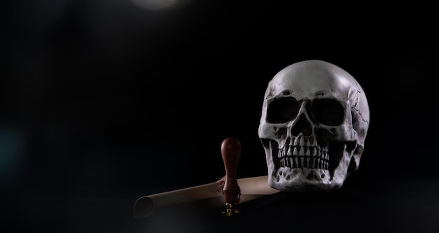 Halloween human skull on an old wooden table over black background Shape of skull bone for Death head on halloween festival which show lastwill letter stamp interitance ghost spirit copy space