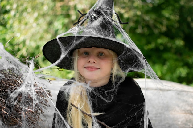 Halloween and kids. Girl in a black hat with spiders and cobwebs, portrait