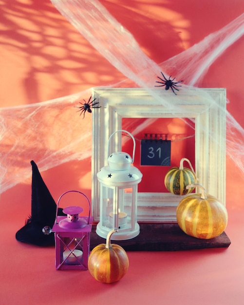 Halloween, a lantern with a burning candle, pumpkins, a witch's hat cobwebs with spiders