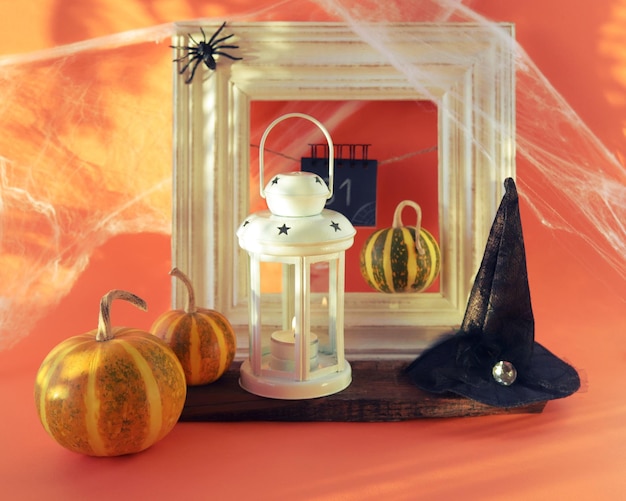 Halloween, a lantern with a burning candle, pumpkins, a witch's hat, cobwebs with spiders