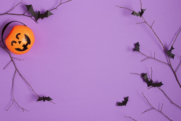 Halloween paper bats flying on tree branch on purple background top view