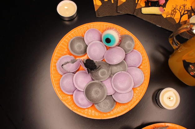 Halloween party Orange plate filled with black and purple sweets shaped like UFO A jelly eyeball