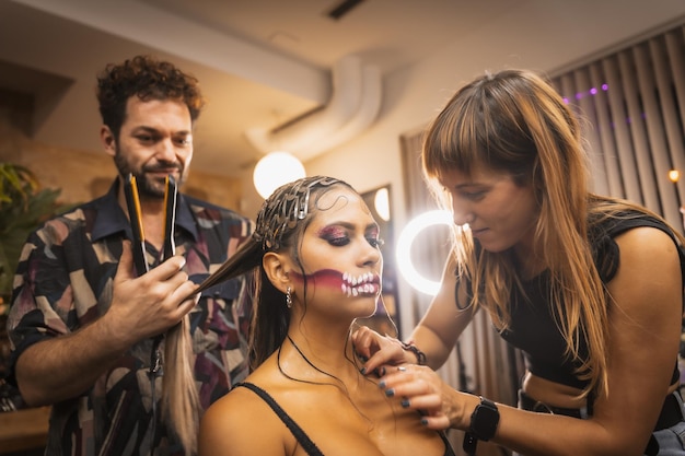 Halloween party preparations stylist and hairdresser working on makeup and hairstyle in beauty salon