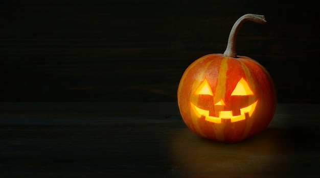 Halloween pumpkin on a dark wooden table. Halloween background. Banner. Copy space.