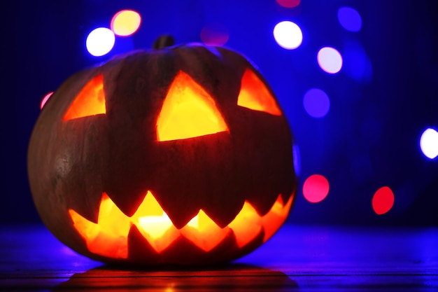 Halloween Pumpkin on table on dark color background with multicolor lights