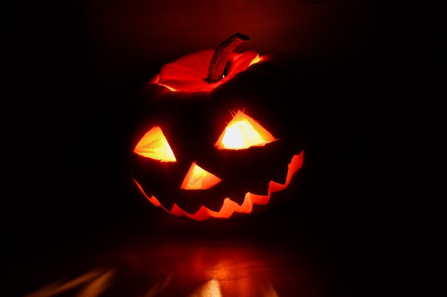 Halloween pumpkin with carved glowing face in the dark.