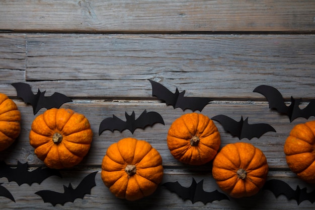 Halloween pumpkins and black vampire bats on a wooden background