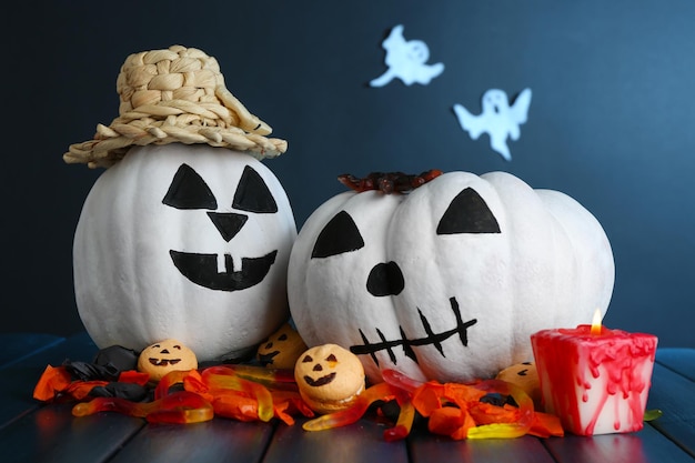 Halloween pumpkins and candles on wooden table on dark color background