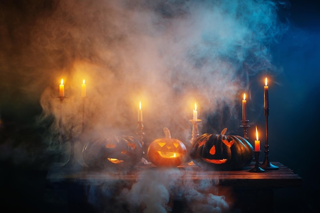 Halloween pumpkins with burning candles on dark background