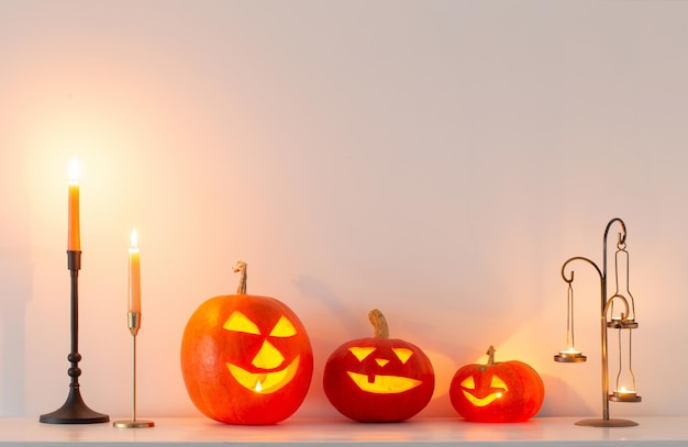 Halloween pumpkins with burning candles in white interior