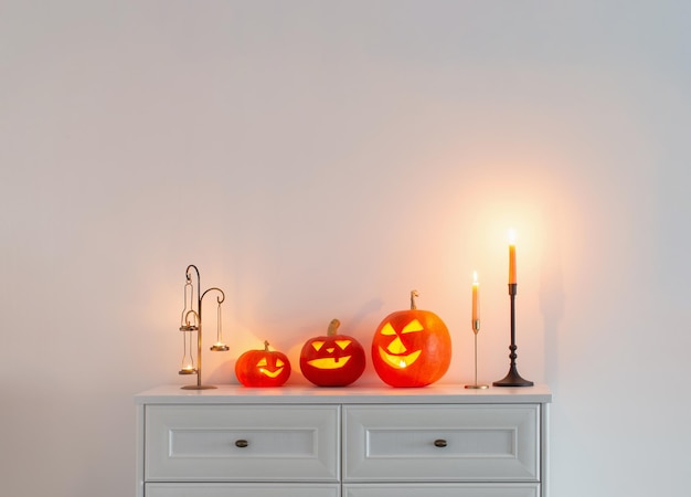 Halloween pumpkins with burning candles in white interior