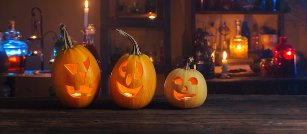 Halloween pumpkins with candles and magic potions at night indoor