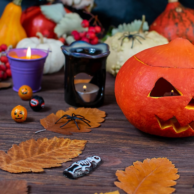 Halloween pumpkins on a wooden dark table with spiders candles pumpkins leaves on a blurred background Selective focus Halloween concept