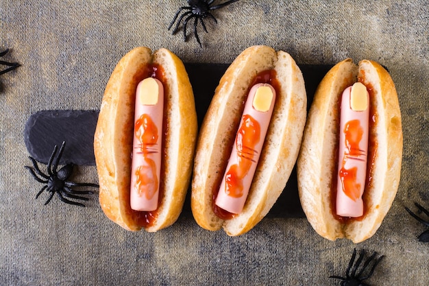 Halloween recipe hot dogs with sausage fingers in ketchup on a slate on the table Top view Closeup