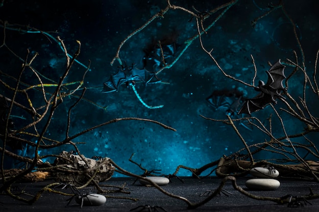 Halloween scary dark blue background with twisted branches bats stones and spiders copy space