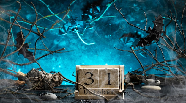 Halloween scary dark blue background with twisted branches bats stones and spiders smoke and october calendar copy space