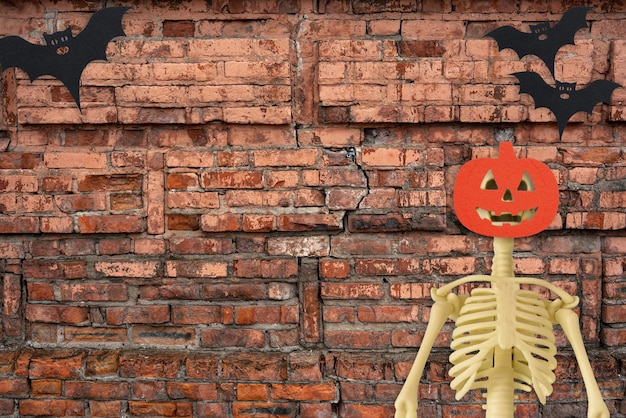 Halloween skeleton and bat on old red brick background