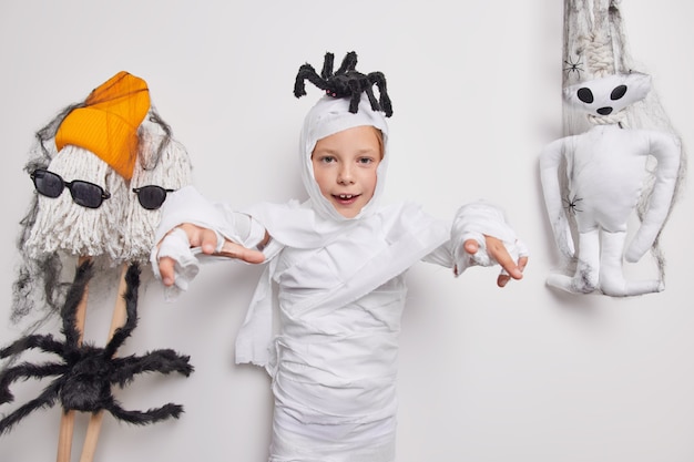 Halloween. Spooky little child ghost does trick or treat has spider on head says I will eat you ready to celebrate party poses on white 