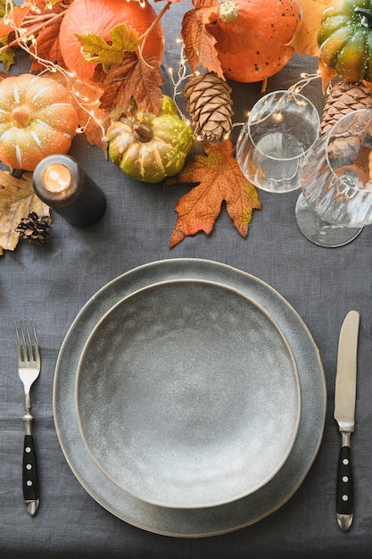 Halloween and thanksgiving day table settingfestive dinner decoration fallen leaves pumpkins on gray