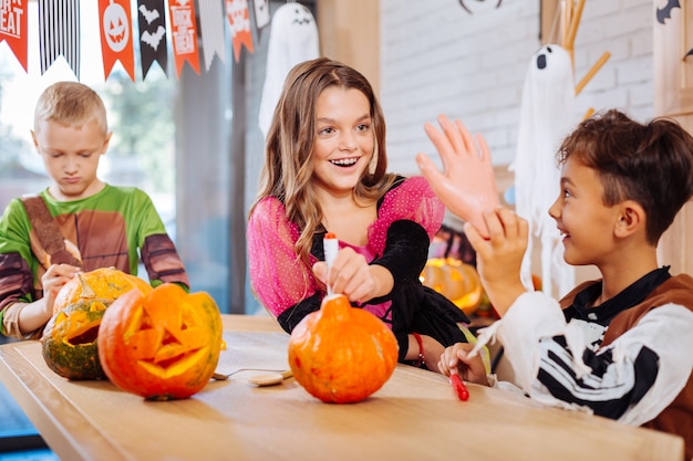 Halloween toys. Three children wearing nice costumes feeling funny while holding scary Halloween toys for the party