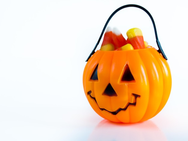 Halloween treat bag filled with candy corn candies on white background.