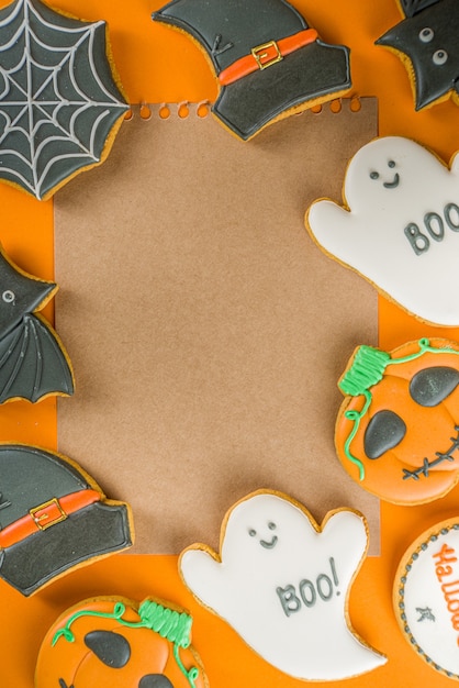 Halloween treats background with sugared Gingerbread cookies and candies, Trick or treat concept top view copy space, trendy bright orange color background