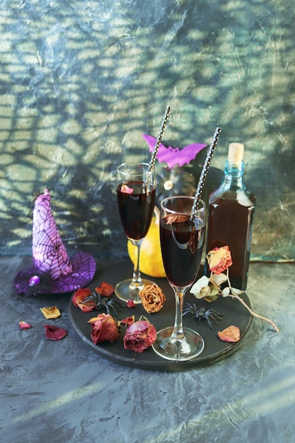 Halloween wine in glasses and a bottle pumpkins mystical decorations dry rose flowers