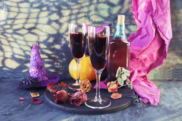 Halloween wine in glasses and a bottle pumpkins mystical decorations dry rose flowers