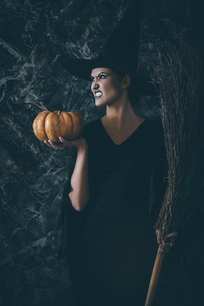 Photo halloween witch holding a pumpkin and a broom