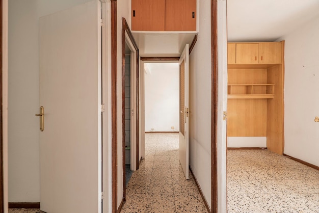 Hallway of a residential house with vintage terrazzo flooring old wooden cabinets and white painted wooden doors