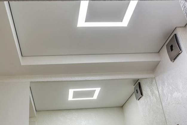 Halogen spots lamps on suspended ceiling and drywall construction in in empty room in apartment or house Stretch ceiling white and complex shape