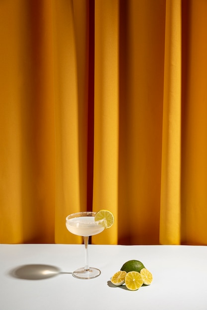 Halved lemon slices near the cocktail on table against curtain