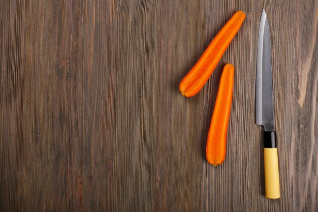 Photo halves of carrot with knife on wooden background