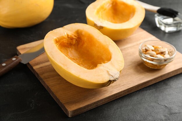 Halves of fresh spaghetti squash on black table Cooking vegetarian dish