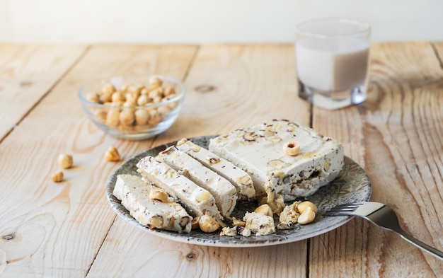 Halwa with hazelnuts on grey plate and wooden background