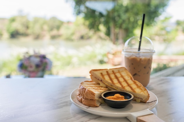 Ham cheese sandwich with custard sauce and ice coffee on marble