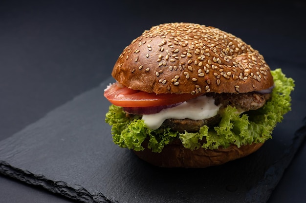 Hamburger on a black board on a black wooden background