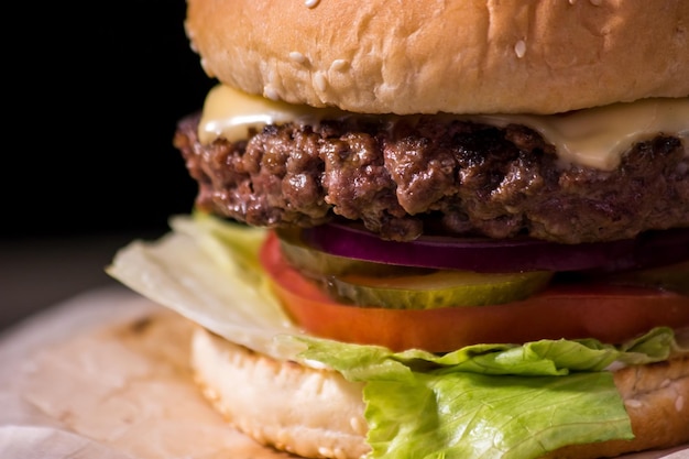 Hamburger closeup on black background fresh vegetables and grilled meat