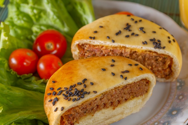 Hamburger meat, gergilim, lettuce and tomatoes on a porcelain plate