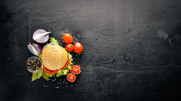 Hamburger with cheese meat tomatoes and onions and herbs On Wooden background Top view Free space