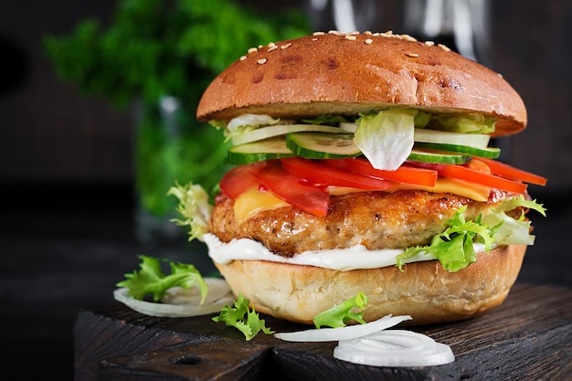 Hamburger with chicken burger meat cheese tomato cucumber and lettuce on wooden background Tasty burger Close up