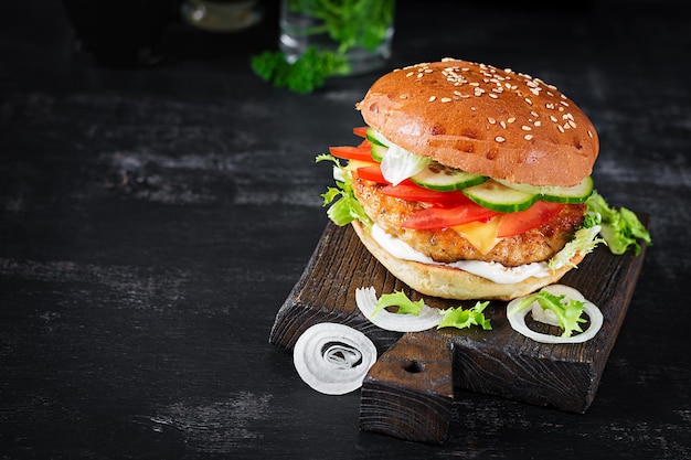 Hamburger with chicken burger meat cheese tomato cucumber and lettuce on wooden background Tasty burger Close up