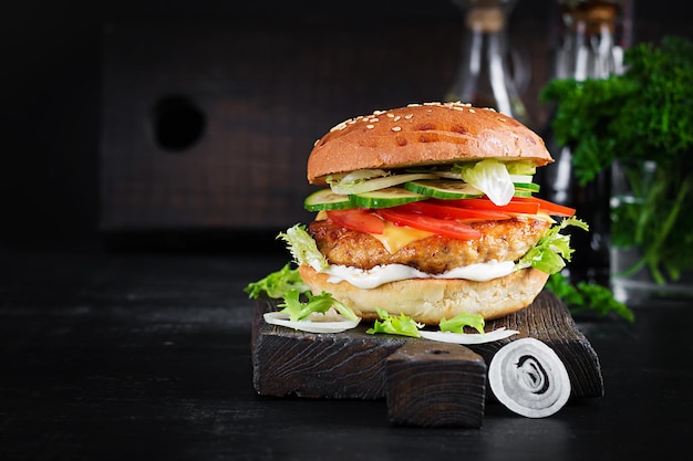 Hamburger with chicken burger meat cheese tomato cucumber and lettuce on wooden background Tasty burger Close up