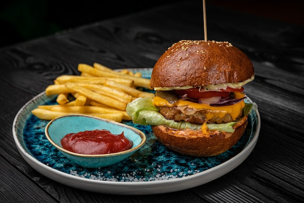 Hamburger with french fries and sauce on a dark wooden table