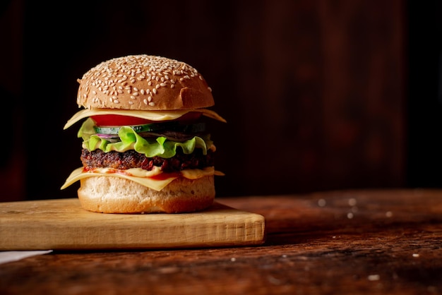 Hamburger with grilled meat cheese green salad and tomato Wooden background Hamburger Day