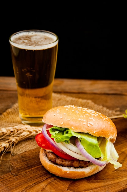 hamburger with mug of beer on wooden table