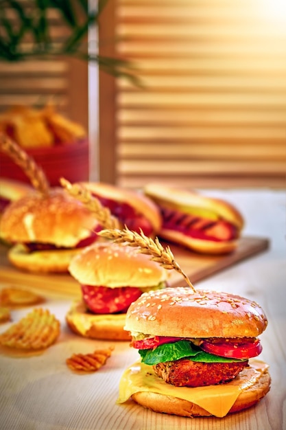 Hamburgers chips and Hot dogs on wooden board in sunny cafe