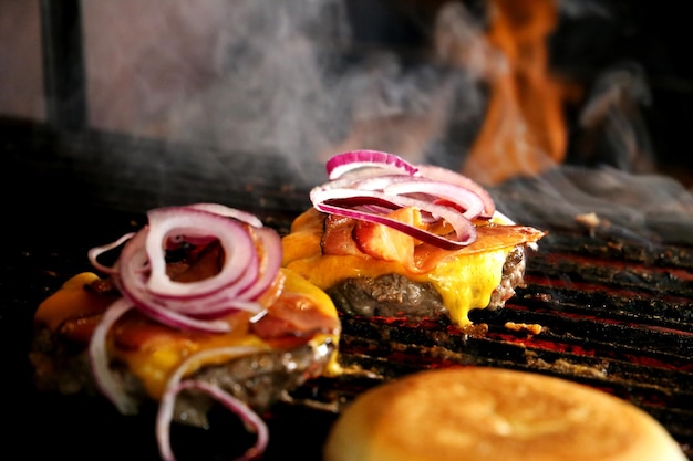 Hamburguer Grilled brazilian hamburger on parrilla with melted cheese bacon red onion and pickles