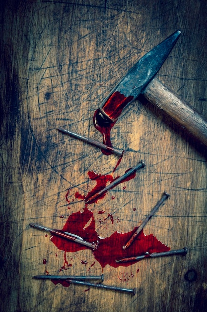 Hammer and bloody nails on a wooden