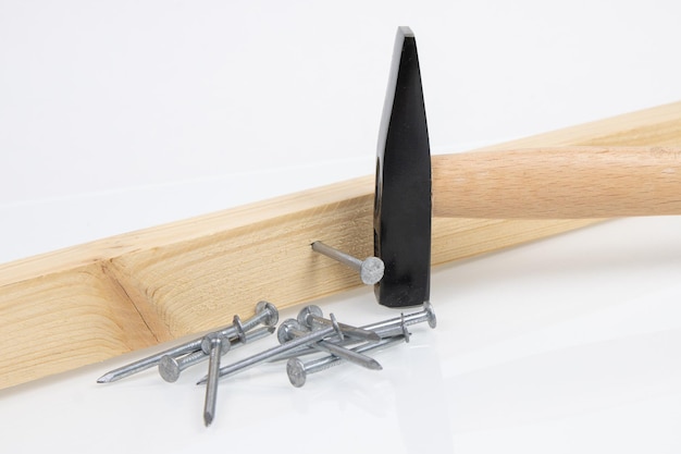 Hammer board and construction nails on white background